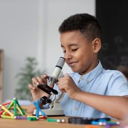 criança-negra-com-lupa-analisando-lapis-e-brinquedos-encima-da-mesa